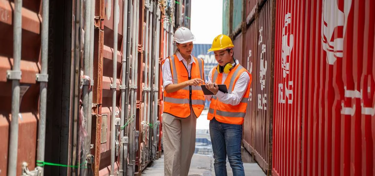 Logistics worker beside shipping containers